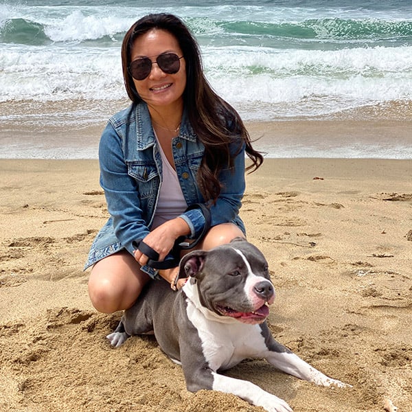 Tracie Noriega posing at the beach with her dog.